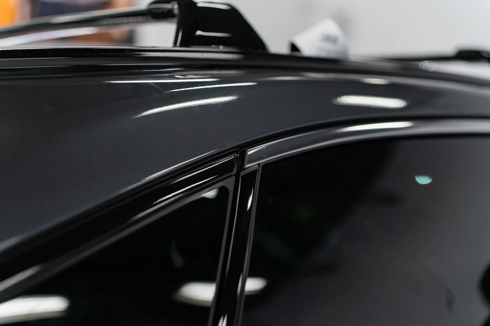 Glossy black vehicle paint under shop lighting