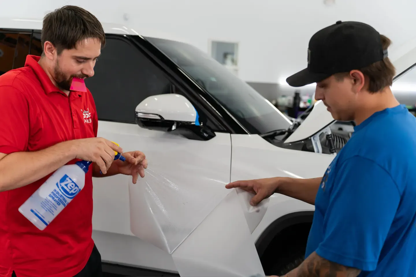 PPF Pros installers applying paint protection film to a white vehicle in their Gilbert shop
