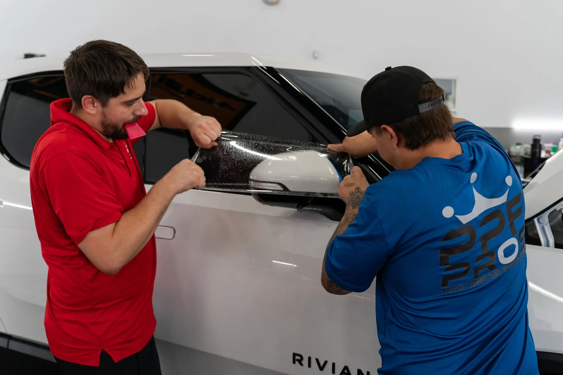 Technicians installing paint protection film on a white vehicle