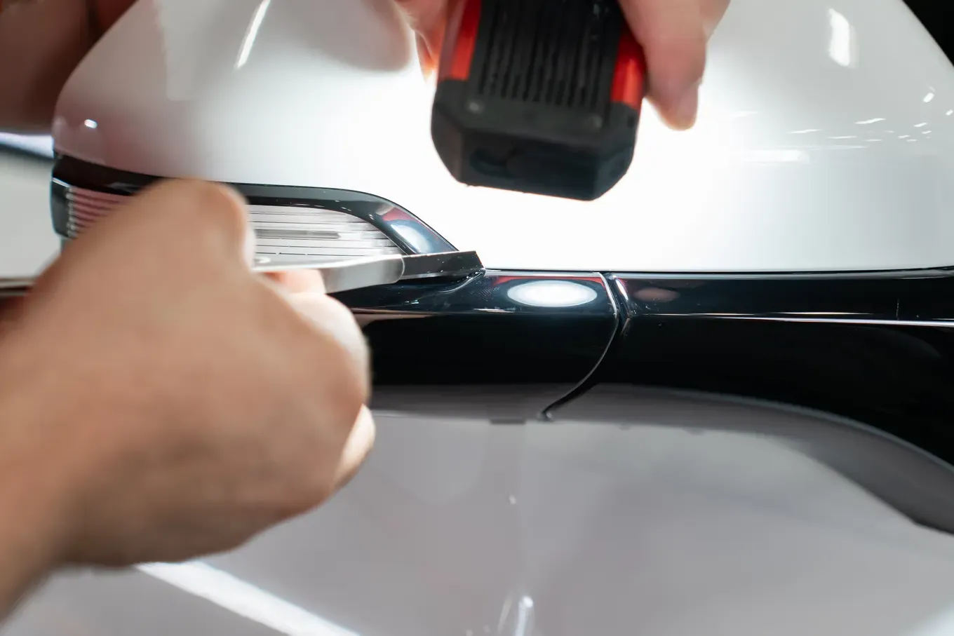 Technician finishing paint protection film around a vehicle detail
